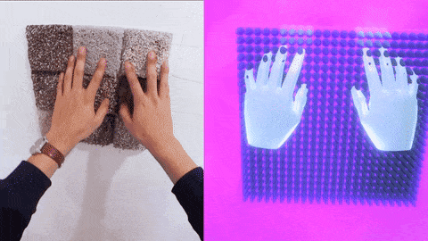 Video of a person draging their hands along a patch of carpet mounted to the wall.