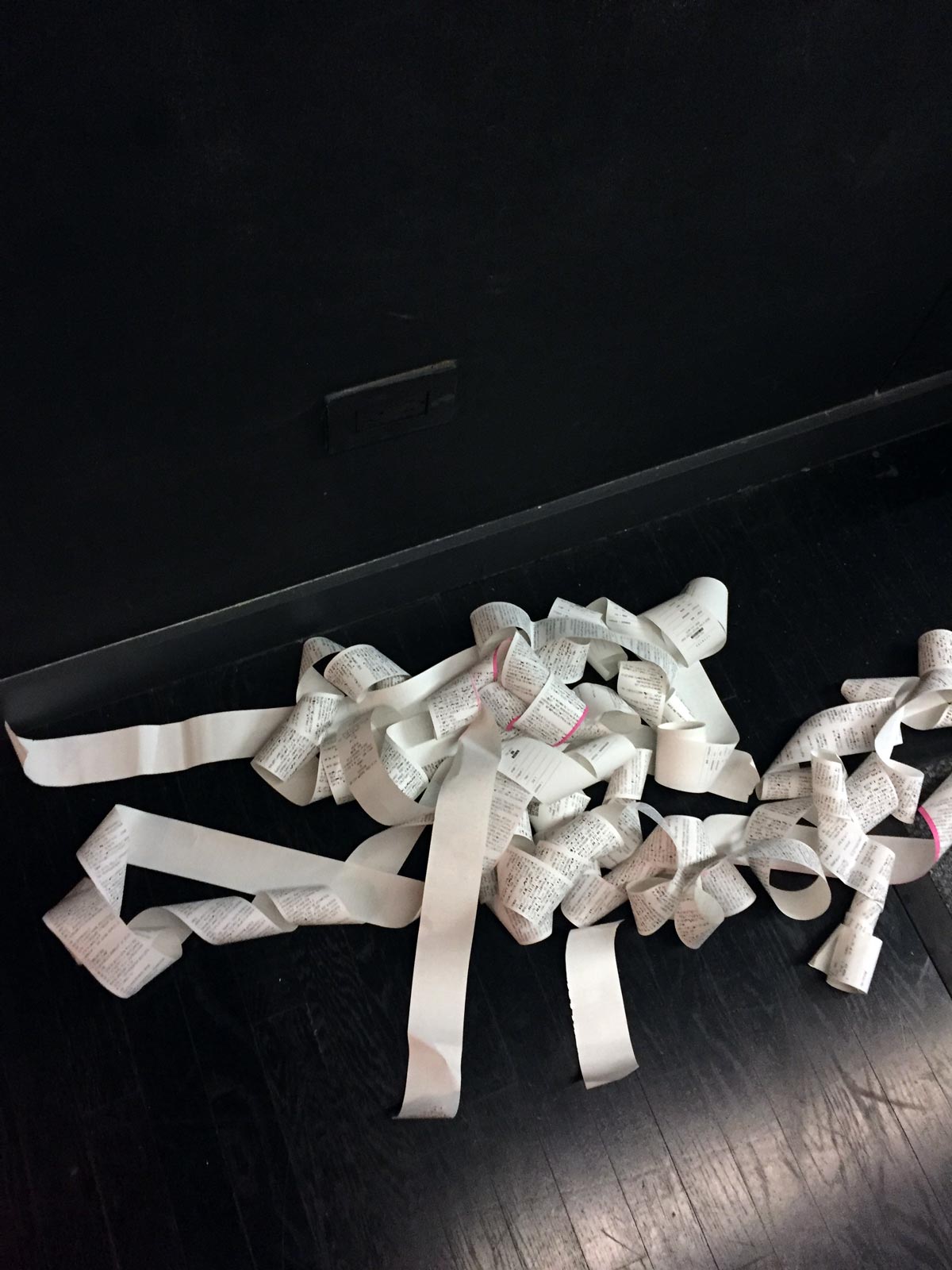A pile of printed thermal paper, gathered on the floor. This was the result of a bug in the code that forced all the printers to print gibberish while the device was plugged in overnight.
